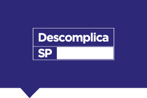 Logo retangular azul com letras brancas escrito "Descomplica SP", aplicado em fundo azul.